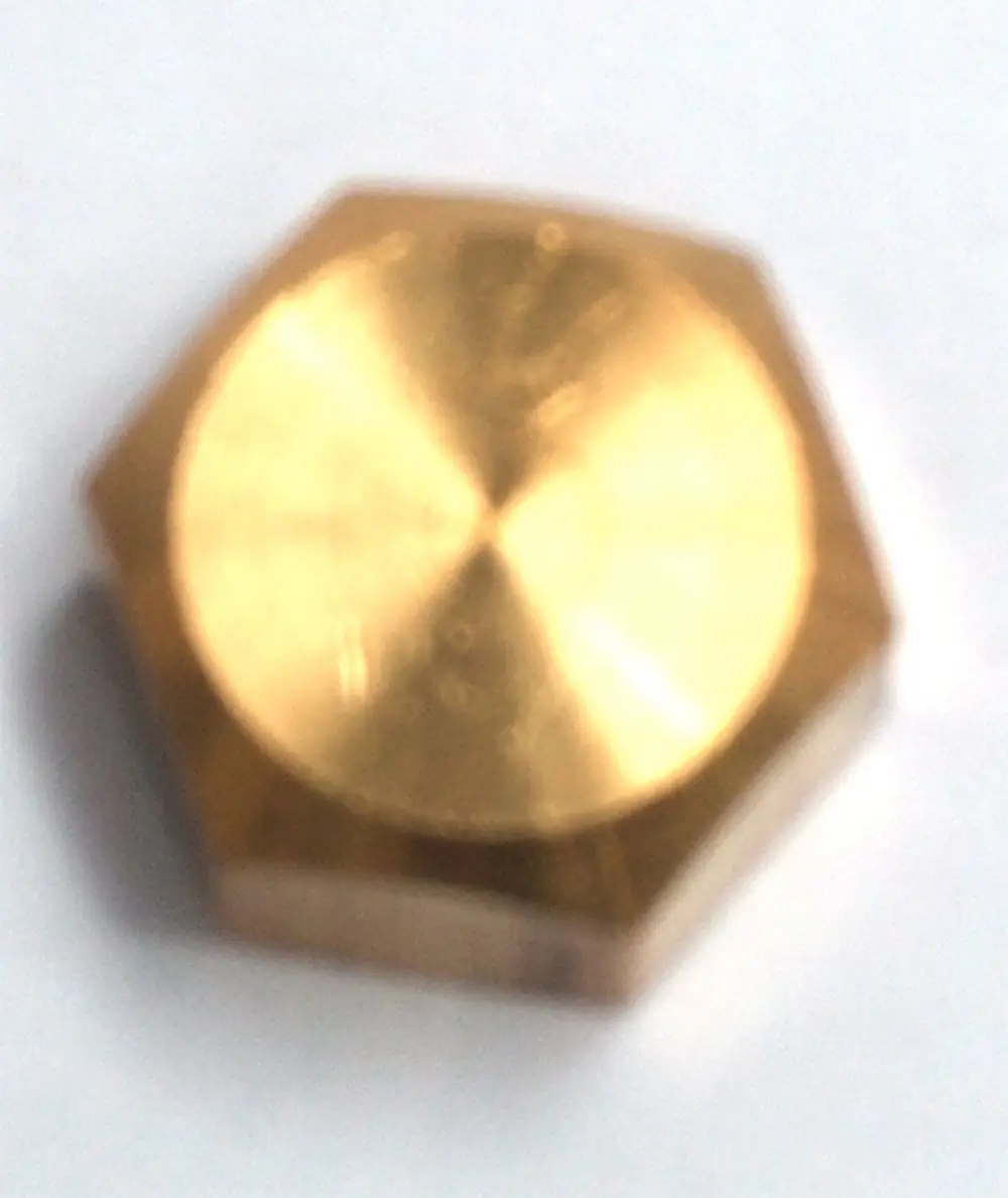 Hexagonale Metallkappe in Goldfarbe, möglicherweise aus Messing, auf weißem Hintergrund. Teil eines Daikin Systems zur Ventilabdeckung.